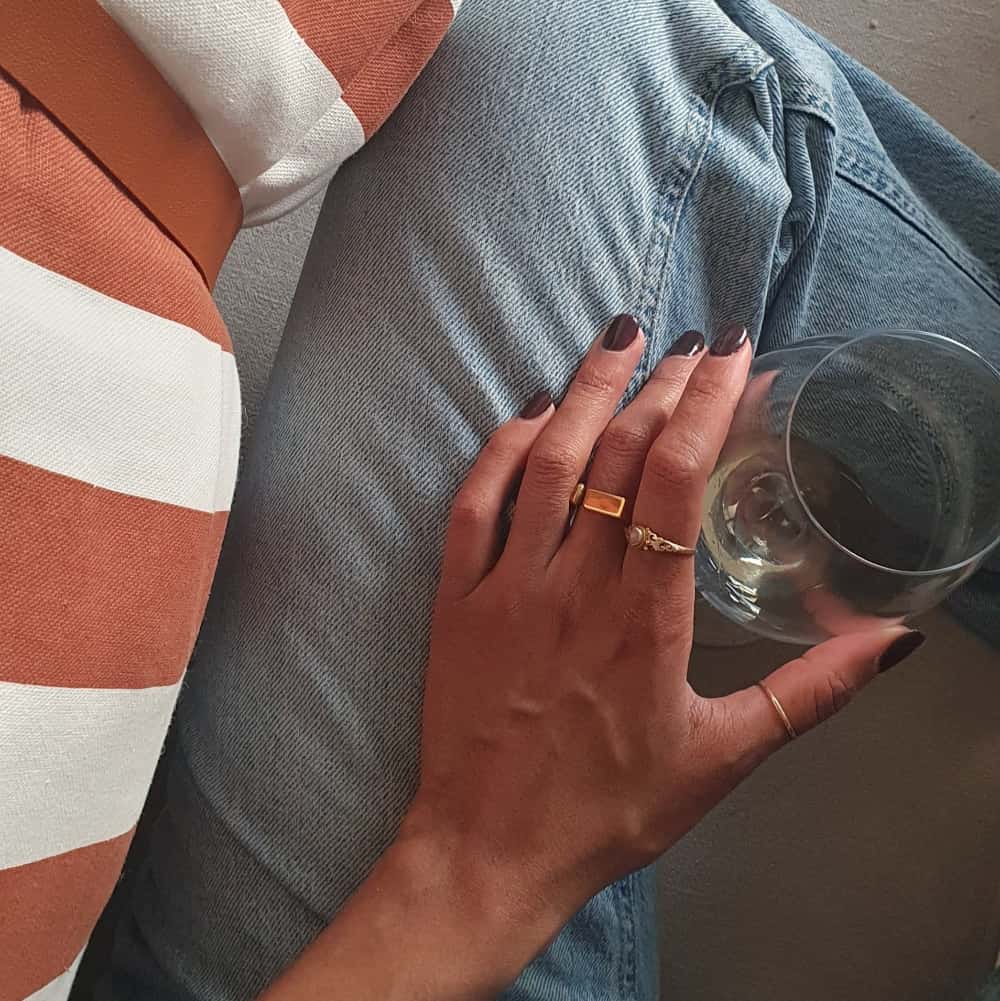 Hand holding a glass of wine with denim jeans and striped fabric in the background