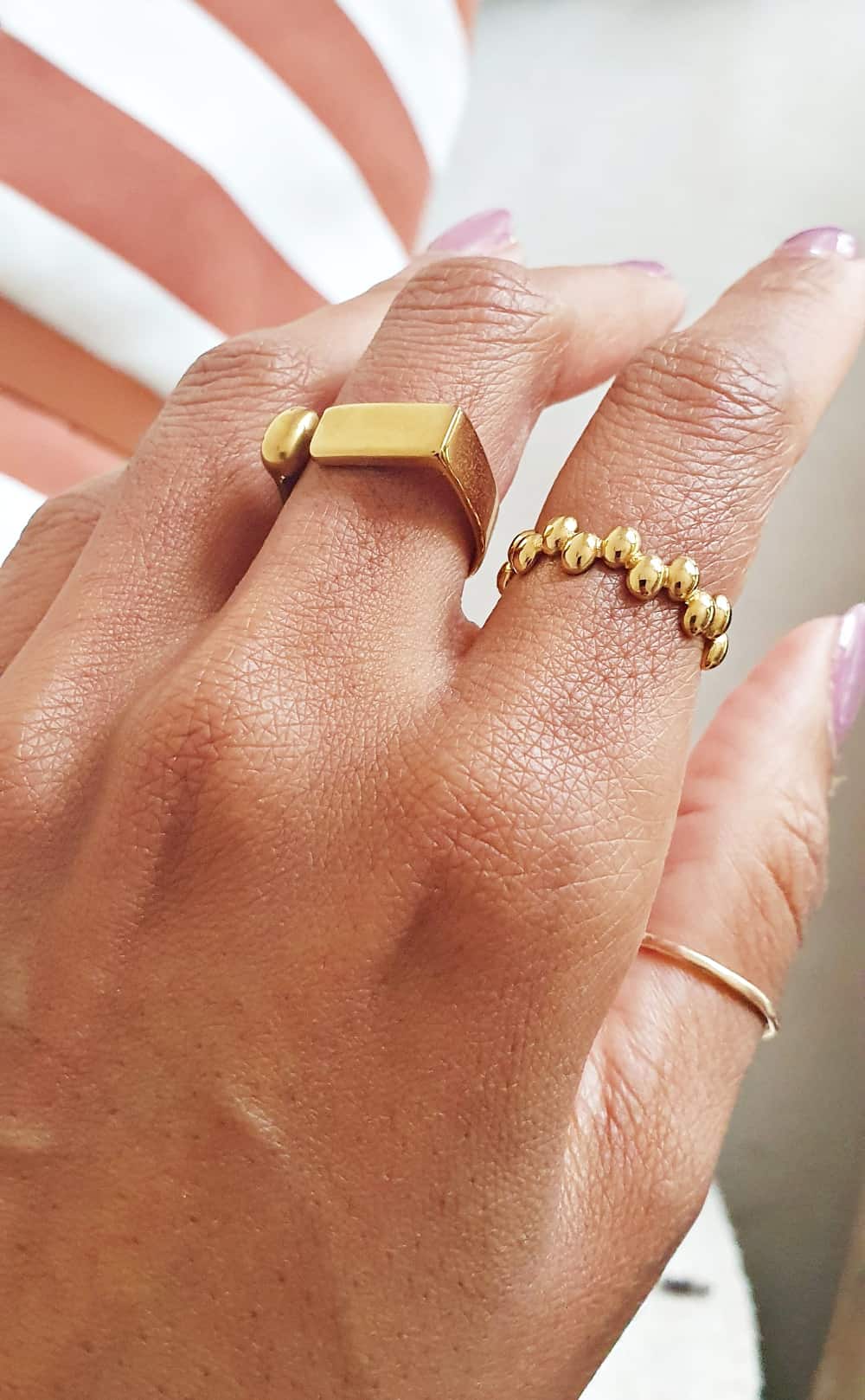 Hand wearing gold rings with a blurred background